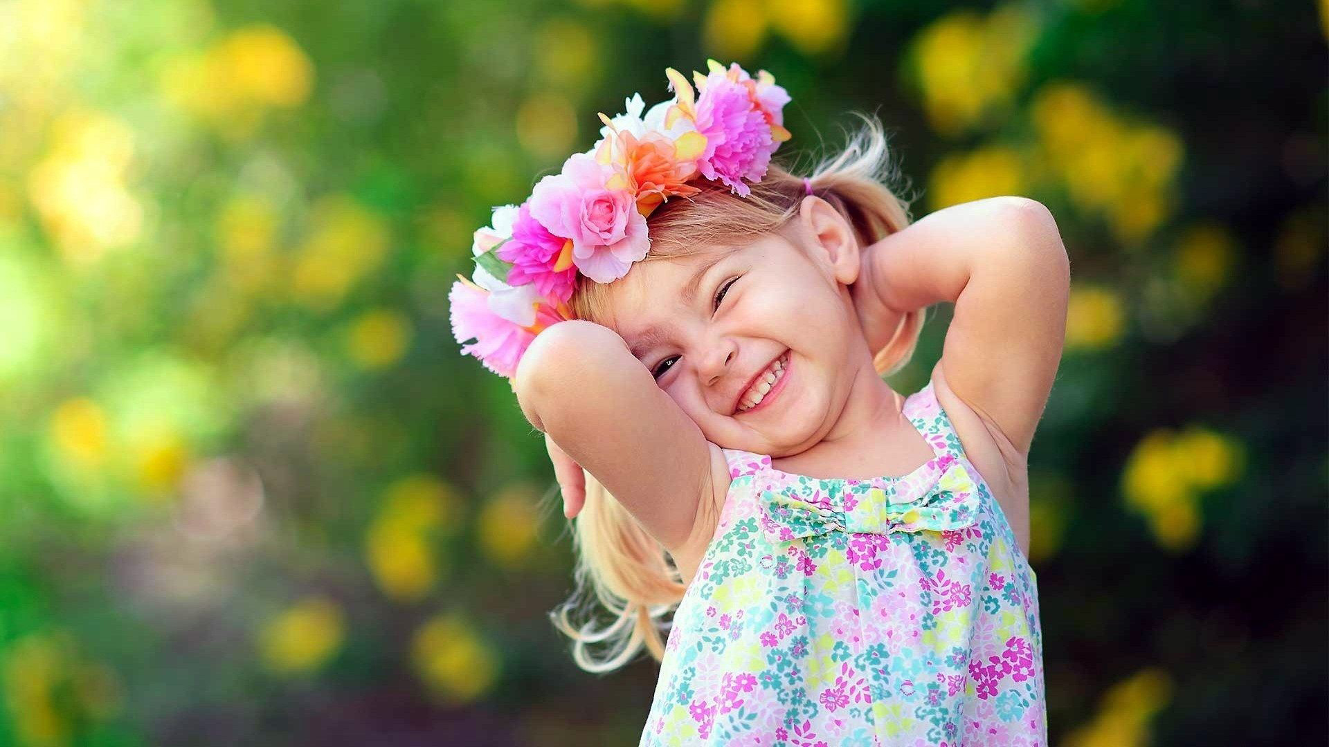 Smiley Cute Girl Child Is Standing In Blur Yellow Flowers Wallpaper Wearing Flowers Printed Dress 2K Cute