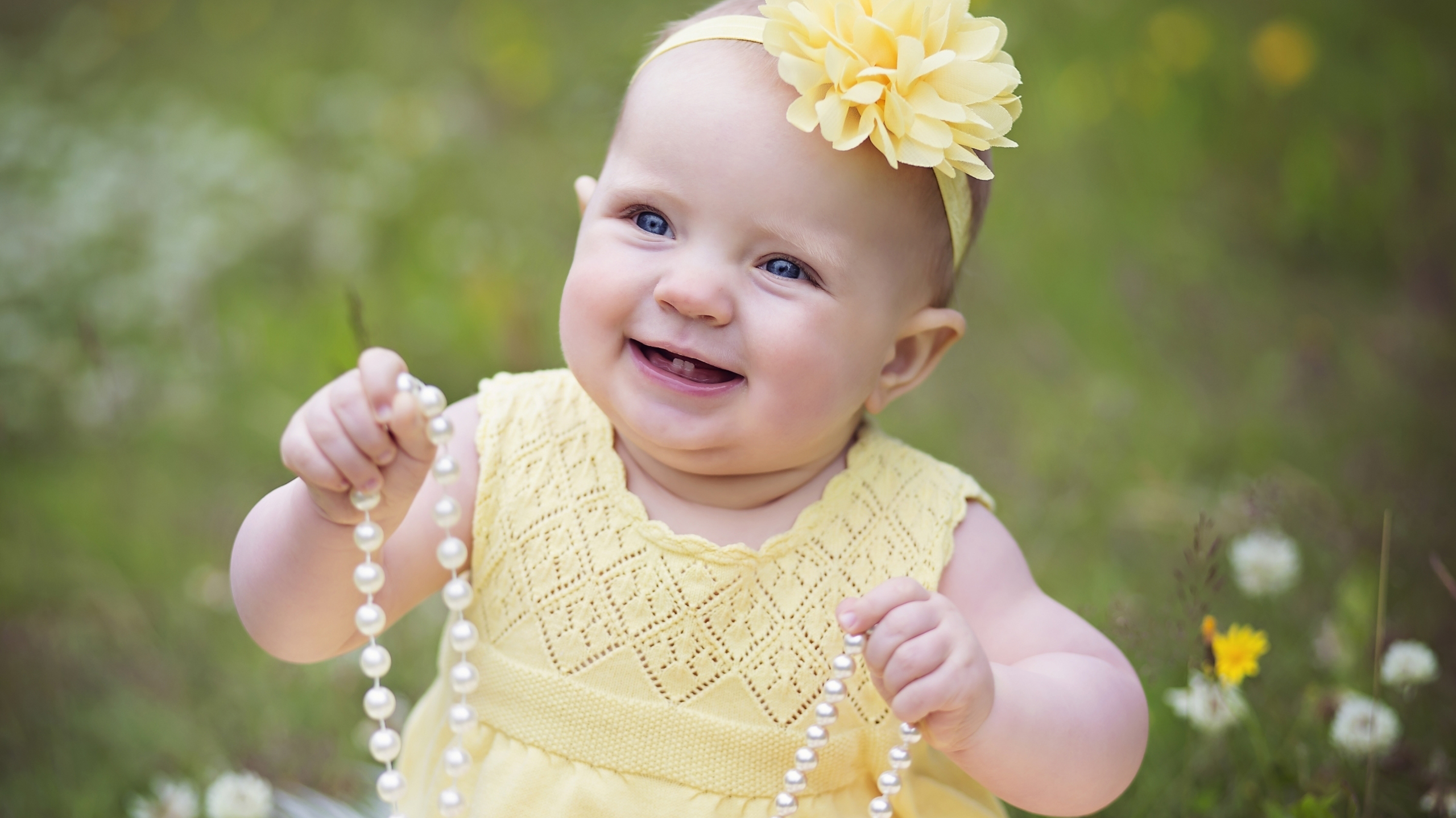 Smiley Baby Girl Child With Beads Is Wearing Yellow Dress And Headband In Blur Wallpaper 2K Cute