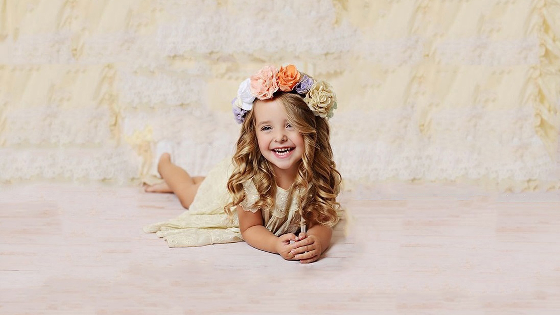 Smiling Curly Hair Cute Little Girl Is Lying Down On Floor Wearing Light Yellow Dress And Wreath 2K Cute