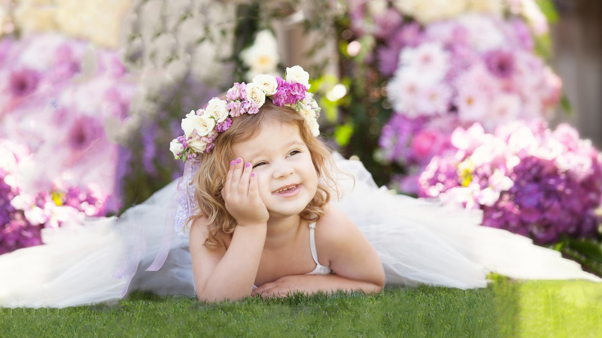 Cute Smiley Girl Is Lying Down On Green Grass Holding Face With Hand Wearing White Dress And Flowers Wreath 2K Cute