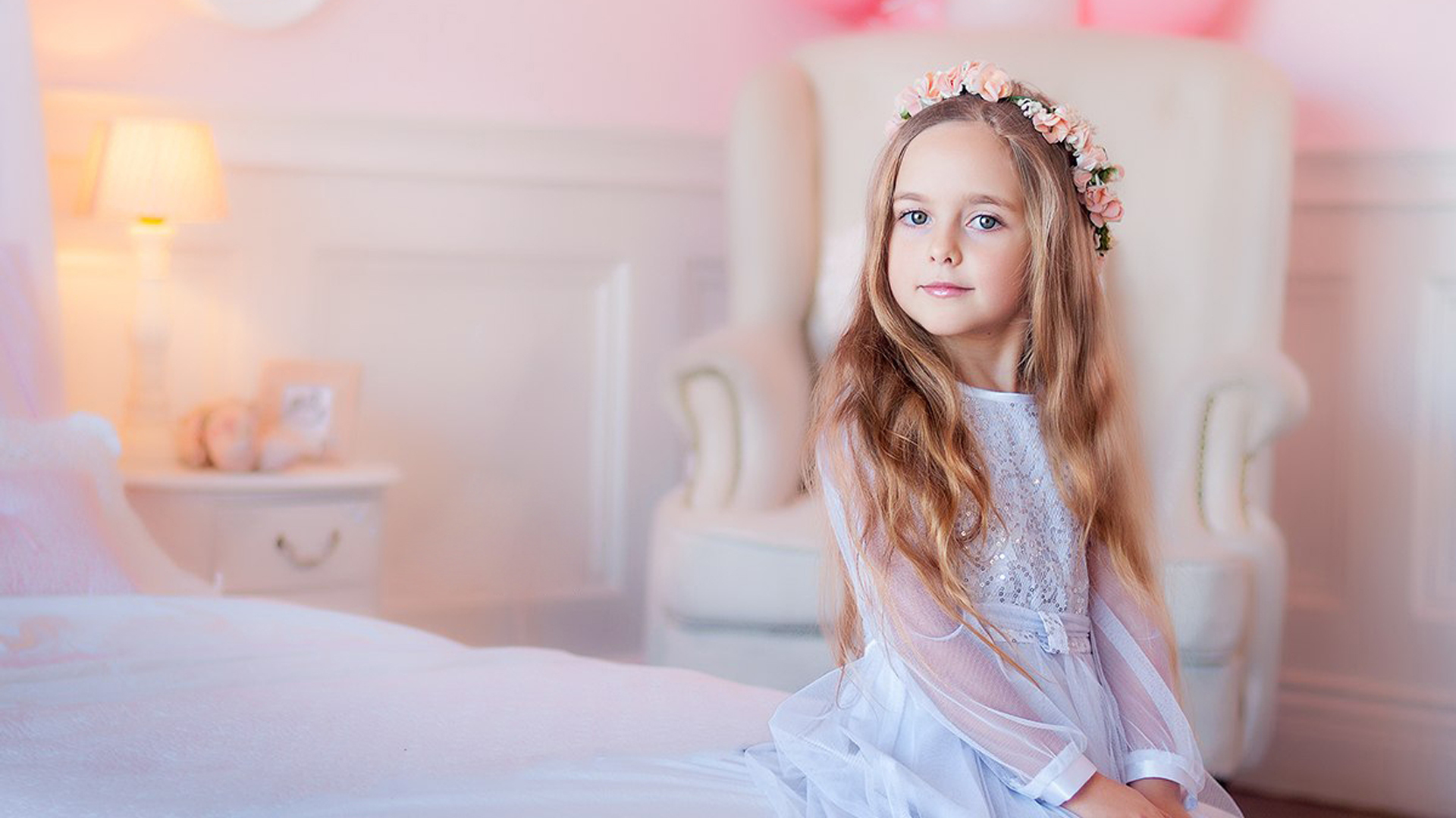 Beautiful Little Girl Is Sitting On White Bed Wearing White Dress And Wreath 2K Cute