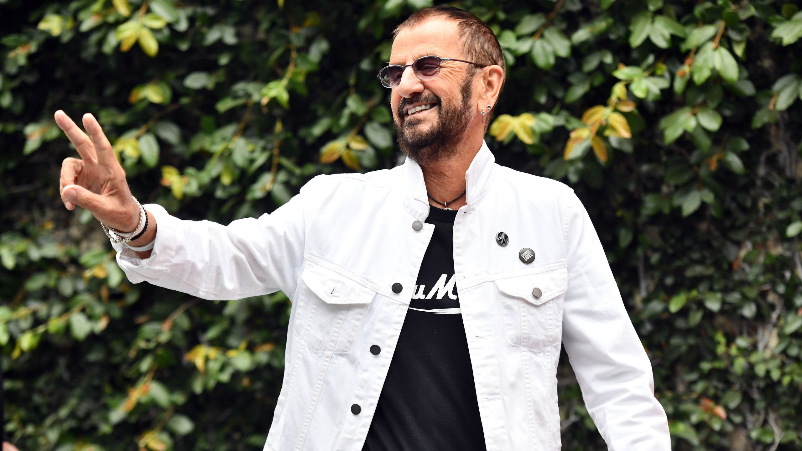 Ringo Starr Is Wearing Black T-Shirt And White Overcoat In Green Leaves Wallpaper 2K Ringo Starr