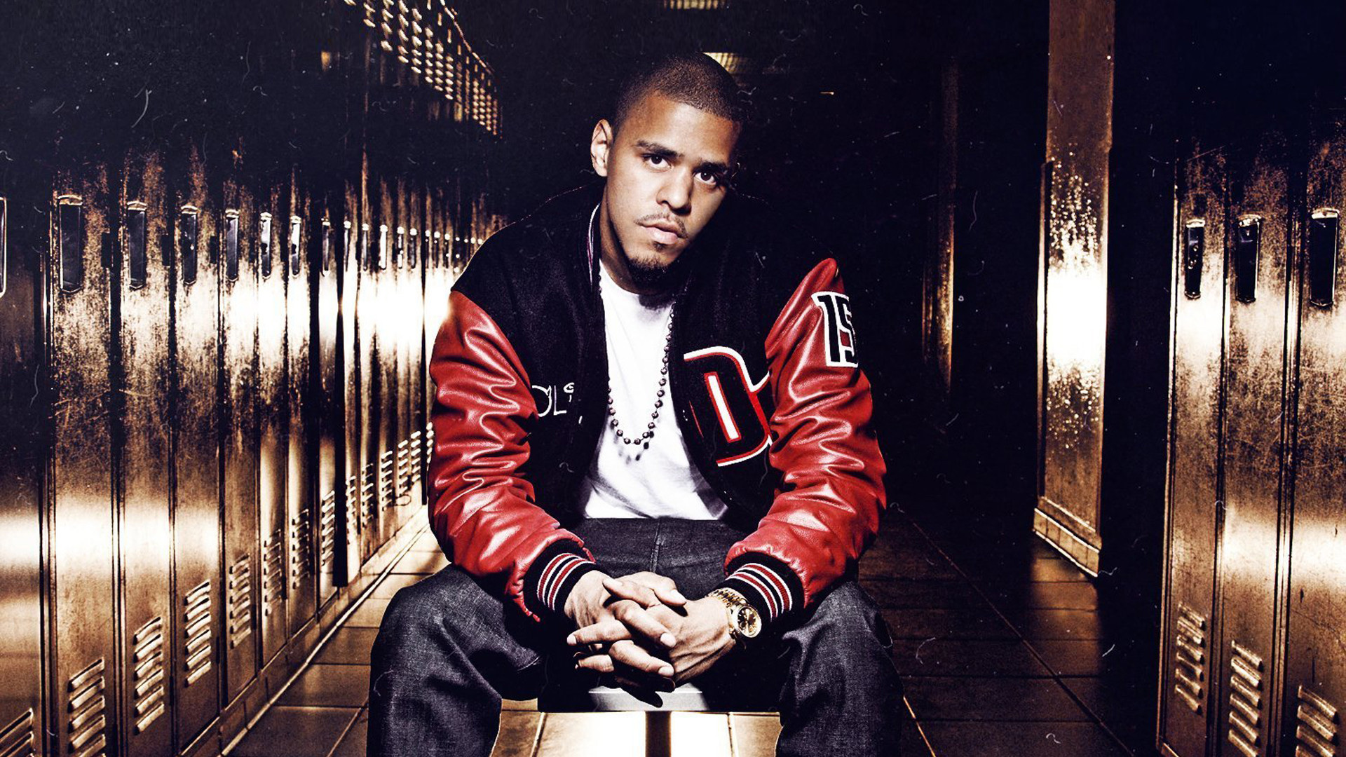 J Cole Is Sitting On Chair Wearing White T-shirt And Red Black Overcoat 2K Music