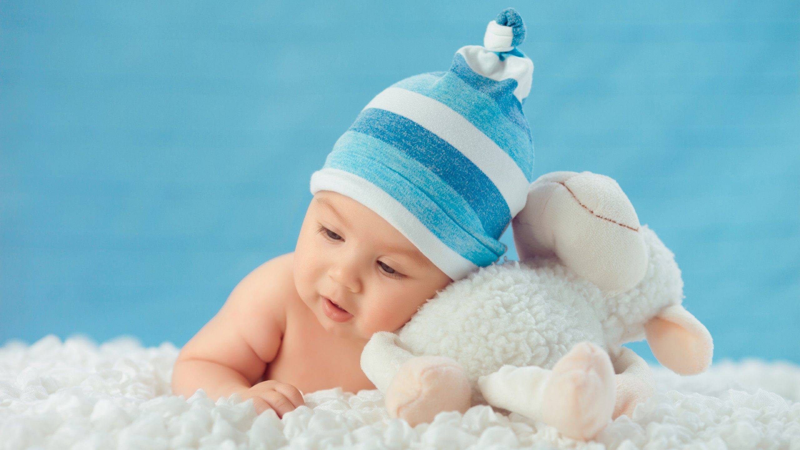 Beautiful Cute Baby Is Lying Down On White Cloth Wearing Blue And White Cap With Bunny Aside In Blue Wallpaper 2K Cute