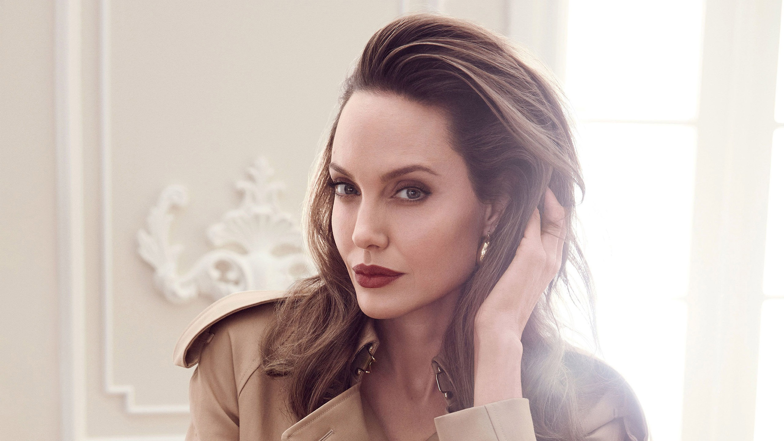 Angelina Jolie Is Posing For A Photo Wearing Brown Coat In White Wallpaper 2K Celebrities