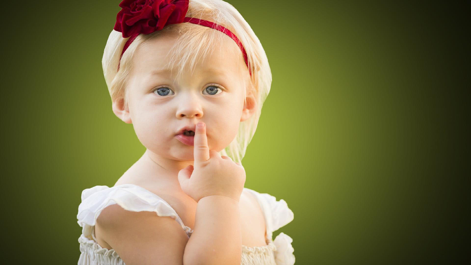 Cute Little Girl Baby Is Keeping Finger On Lips In Green Blur Wallpaper Wearing White Dress And Red Headband 2K Cute