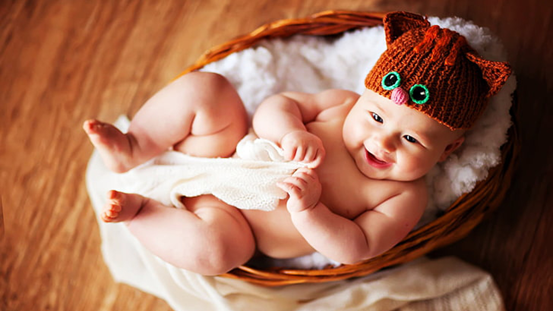 Smiling Cute Child Baby Is Lying Down Inside Basket Wearing Brown Woolen Knitted Cap 2K Cute